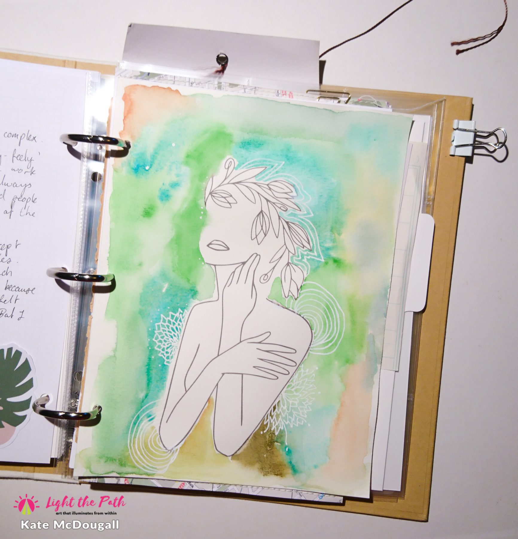 A painted page featuring a line art of a feminine figure, on a background of green and blue watercolour effects.